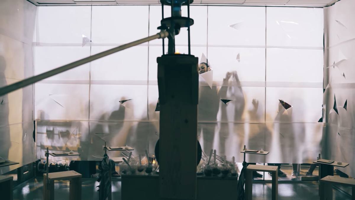 Students gathered around a performance structure they built, paper falling through the air